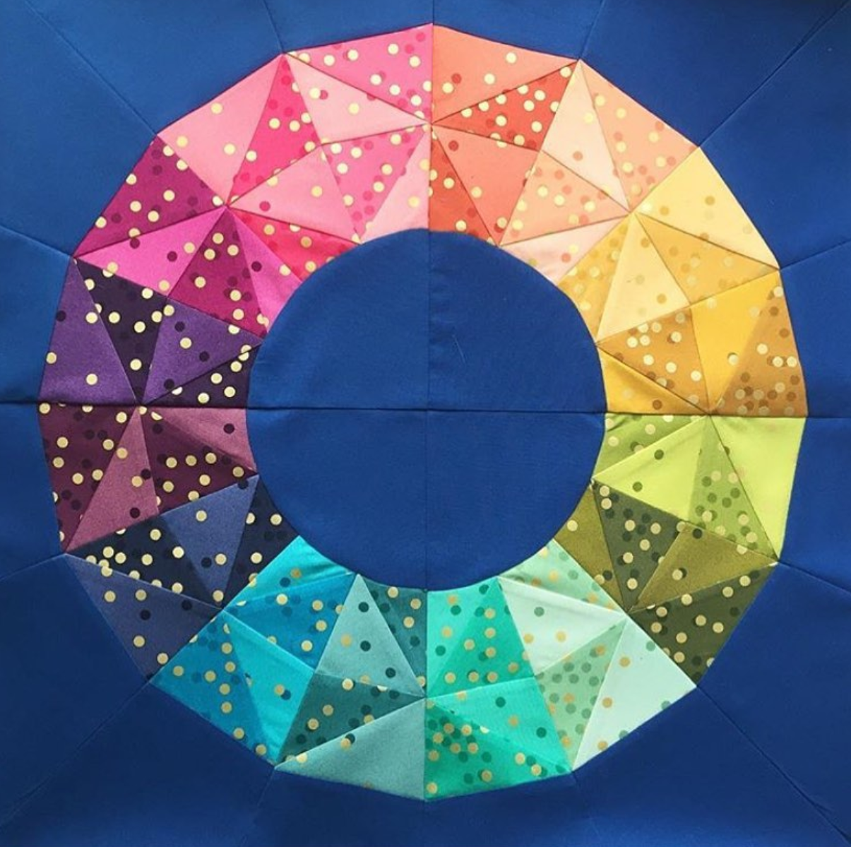 geometric fractured rainbow paper pieced pattern similar to a colour wheel sewn in ombre fabrics