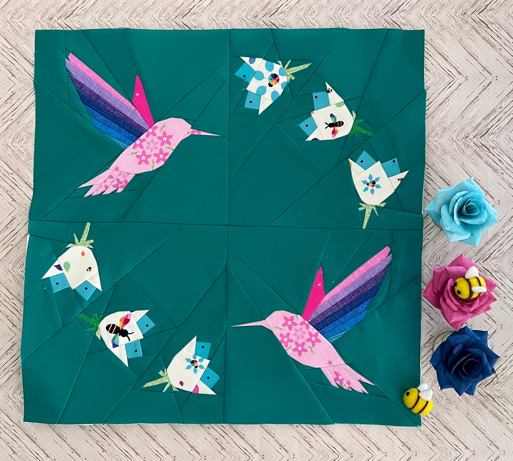 Foundation paper pieced hummingbird wreath quilt block shown in a finished fabric sample. A cheerful FPP design combining flowers and hummingbirds for a bright, nature-inspired quilt.