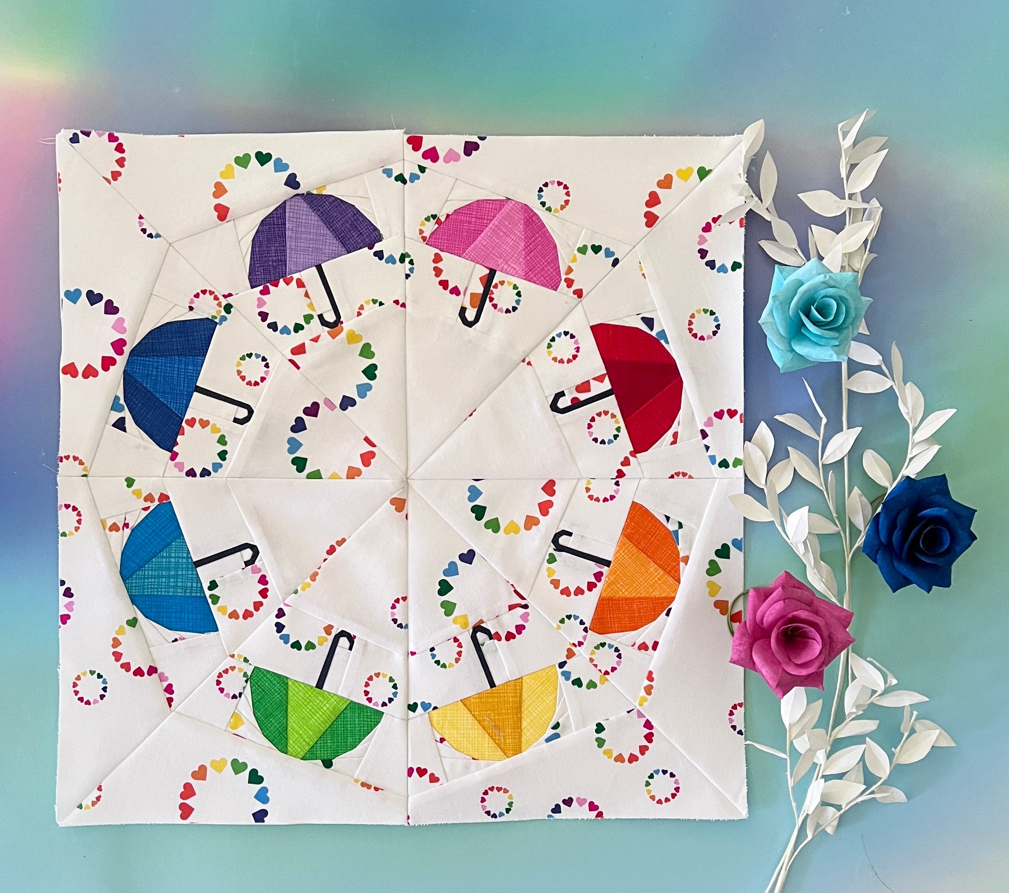 Foundation paper pieced umbrella wreath quilt block shown in a finished fabric sample. A playful FPP design with vibrant umbrellas arranged in a circular pattern for a fun quilt layout.