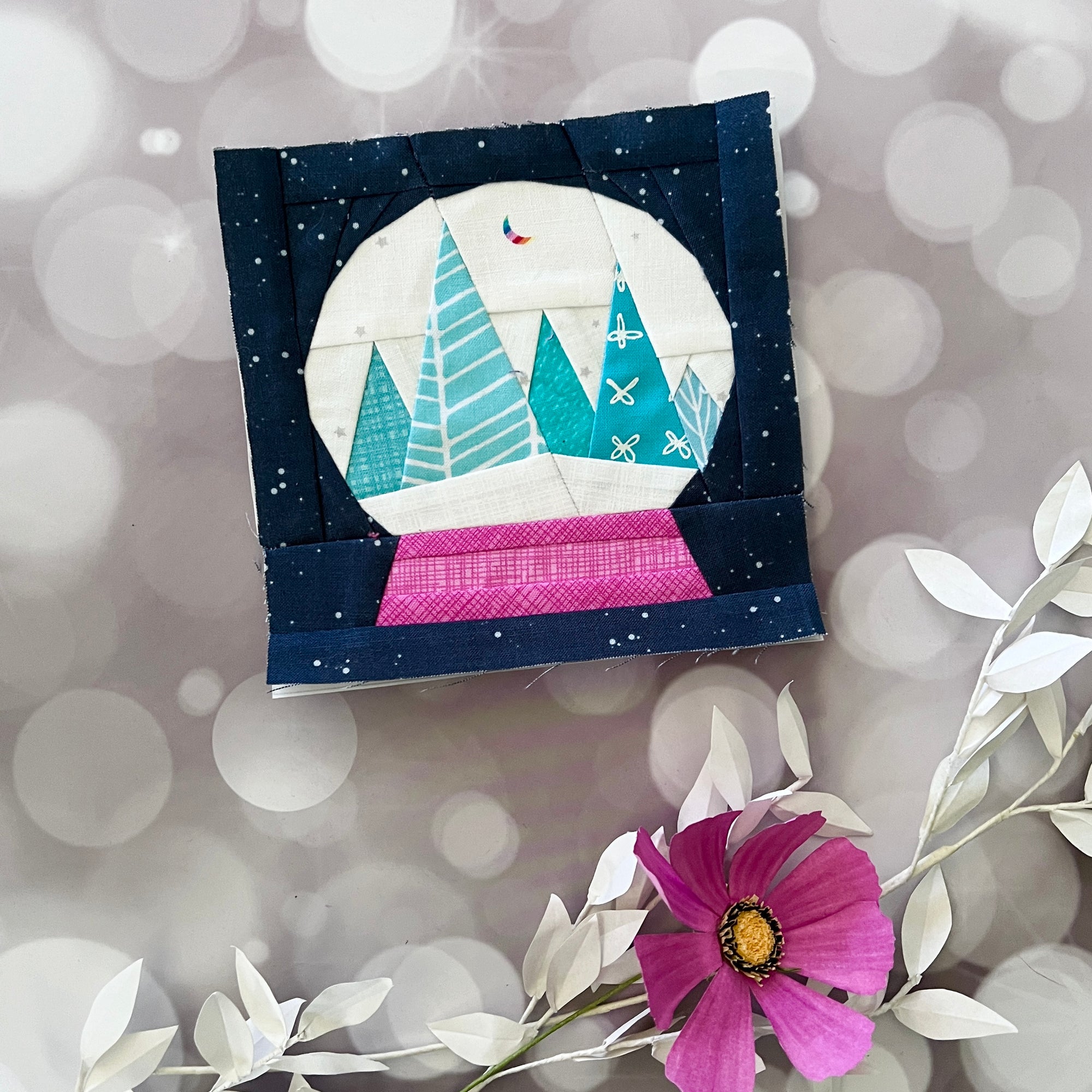 Finished Snow Globe Magic foundation paper pieced quilting pattern stitched quilt block featuring winter trees inside a snow globe.